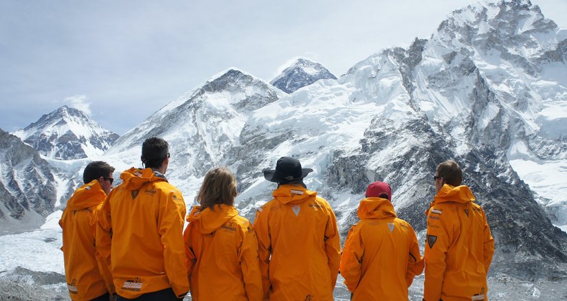 The Everest expedition team looking up at the mountain with their backs to us