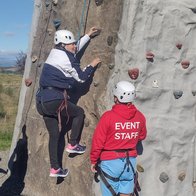 Someone being taught to rock climb on a training wall