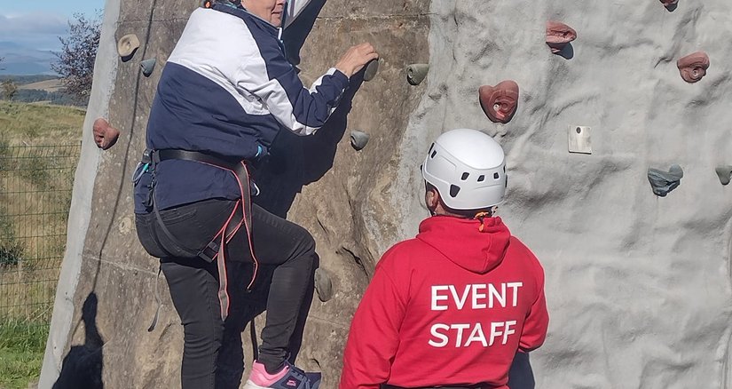 Someone being taught to rock climb on a training wall
