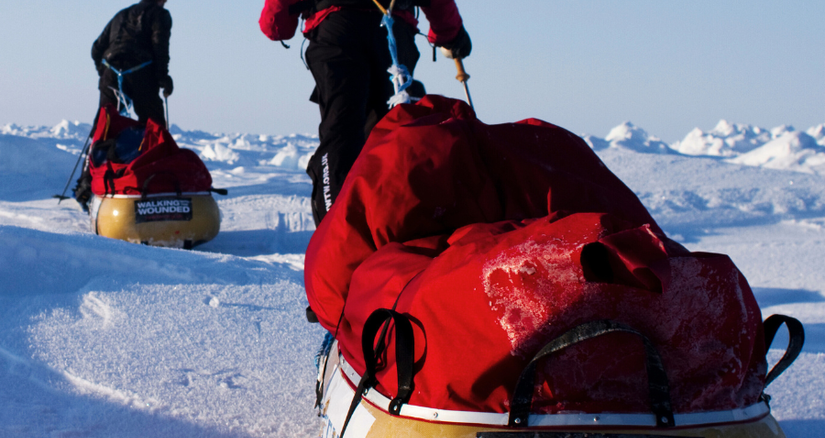 Two men pulling pulks across a polar landscape