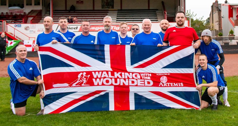 A football team during a tournament holding a WWTW flag