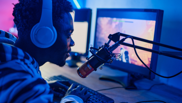 A young male speaks into a microphone as he plays games on his PC.